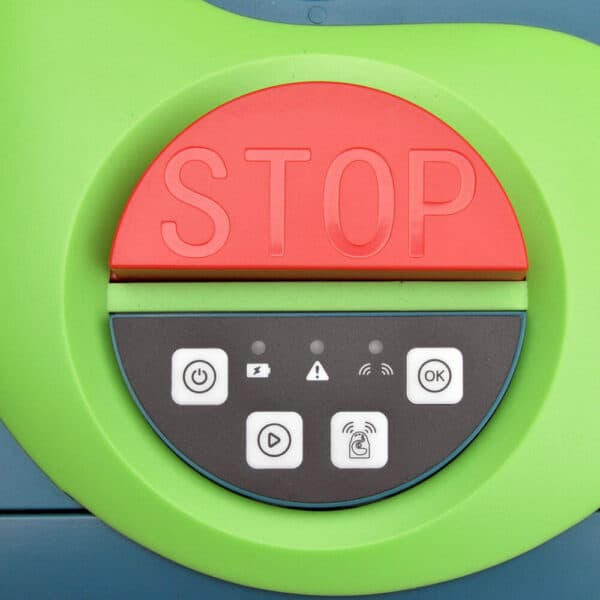 A close-up of a circular control panel on Buddy the Robot Lawn Mower with a green outer ring. The top half is red with the word "STOP" engraved on it. The bottom half is grey, equipped with four white buttons for operating the lawn mower and three small indicator lights.