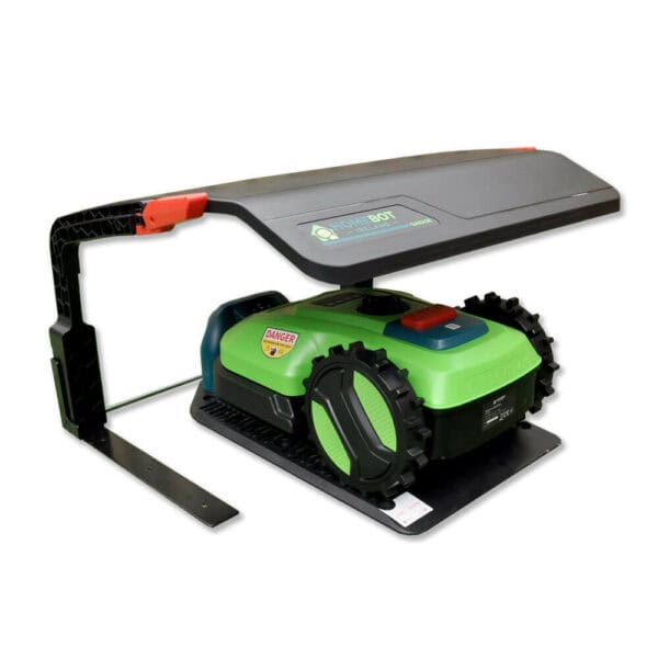 A green Chomper robot lawn mower, with large black wheels rests under a sleek black Rain Shelter HB01. This protective cover is attached to a sturdy frame to shield the mower when not in use. The HB01 features a branding label with HomeBot Ireland logo.